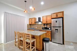 Una cocina con refrigerador y una mesa con sillas. en NEW Condo with Pool and Ocean View Roof near Beach 4 blocks, en La Paz
