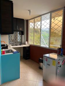 a kitchen with a refrigerator and some windows at La Orquidea Airbnb in Piñas