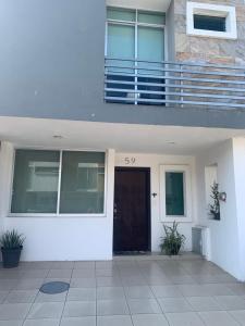 a white house with a door and a balcony at Excelente casa muy acogedora en condominio in Guadalajara