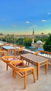 Almas Pyramids Hotel في القاهرة: مجموعة من المقاعد والطاولات الخشبية على السطح