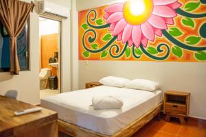 - une chambre avec un lit orné d'une peinture florale sur le mur dans l'établissement Posada Girasol, à Puerto Escondido