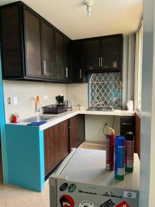 a kitchen with black cabinets and a blue refrigerator at La Orquidea Airbnb in Piñas