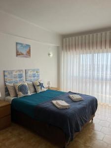 um quarto com uma cama com lençóis azuis e uma janela em Apartamento 806 em Albufeira