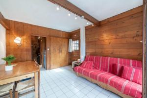 シャモニー・モンブランにあるMontets furnished flatの木製の壁の部屋の赤いソファ