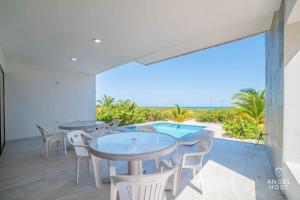 a patio with tables and chairs and a view of the ocean at Beachfront Villas with Private Pool Steps to the Sea! in Chicxulub