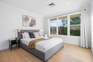 1 dormitorio blanco con 1 cama grande y ventanas en Large 5BD w Amazing Hill view in East Lindfield, en Forestville