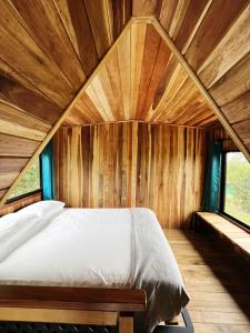 a bed in a room with a wooden ceiling at Myra Chalets in Bijagua