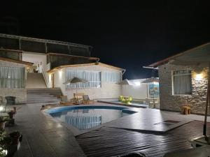 una piscina frente a una casa por la noche en Akas Hotel Apartamentos en Canoas de Punta Sal