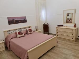- une chambre avec un lit, une commode et un miroir dans l'établissement Abitazione Del Mandorlo, à Trapani