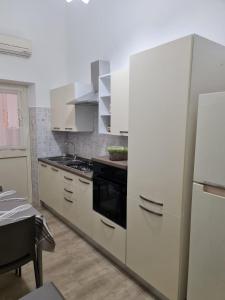  La cuisine est équipée de placards blancs et d'un réfrigérateur. dans l'établissement Abitazione Del Mandorlo, à Trapani