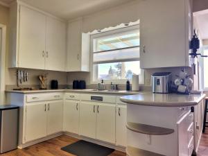 uma cozinha com armários brancos, um lavatório e uma janela em Adventure's Home Base - Hot Tub & King Sized Bed em Port Angeles