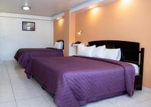 Habitación de hotel con 2 camas y mantas moradas en HOTEL KRISTAL, en Asunción Nochixtlán