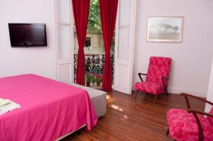 1 dormitorio con cama rosa, silla y ventana en Art house apartments, en Buenos Aires