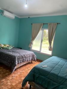 - une chambre avec des murs bleus, un lit et une fenêtre dans l'établissement Casa en La Puntilla, à Belén
