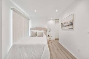 a white bedroom with a white bed and a painting at Modern 1-Bedroom Home in a Prime LA Location in Los Angeles
