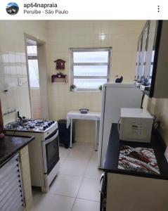 a small kitchen with a stove and a refrigerator at Apartamento inteiro em Peruíbe no centro, próx a praia in Peruíbe
