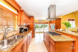 eine große Küche mit Holzschränken und einem Waschbecken in der Unterkunft Breathtaking Chalk Sound Private Pool Sunset Villa in Providenciales