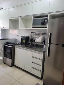 cocina con armarios blancos, microondas y nevera en Egidios AP en São Pedro da Aldeia