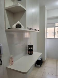 a white kitchen with a shelf and a window at Egidios AP - Centro de São Pedro da Aldeia in São Pedro da Aldeia