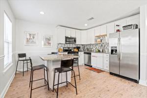a kitchen with a refrigerator and a table and chairs at Cute Downtown Cottage with Large Yard and BBQ plus Smart TVs in St. Augustine