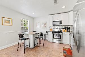 a kitchen with white cabinets and a table and chairs at Cute Downtown Cottage with Large Yard and BBQ plus Smart TVs in St. Augustine