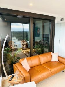 a brown leather couch in a living room with a view at CityNest Iconic View - Free Parking-Gym-Pool-BBQ in Adelaide