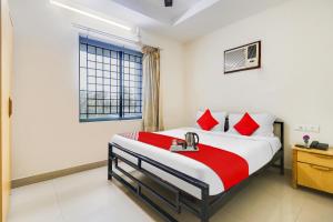 a bedroom with a bed with red pillows and a window at OYO The Safe Hotels in Cochin