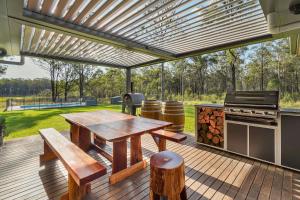 eine Holzterrasse mit einem Picknicktisch und einem Grill in der Unterkunft Mirambeena in Pokolbin