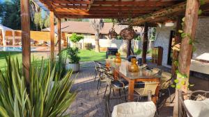un patio con mesa y sillas bajo una pérgola en habitaciones con piscina en tinguiririca san fernando, en San Fernando