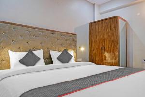 a bedroom with a large white bed with a wooden headboard at Super Townhouse 1935 Hotel Navneeta Grand in Kakarmatha