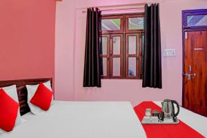 Habitación con cama con almohadas rojas y ventana. en SPOT ON Hotel Kanha Inn en Chaukhandi
