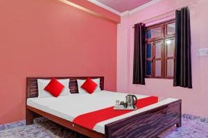 Un dormitorio con una cama con almohadas rojas y una ventana en SPOT ON Hotel Kanha Inn en Chaukhandi