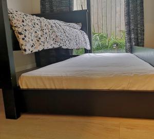 a bed with a black frame and a pillow and a window at W&M Orchid House in Auckland