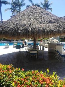 a large straw umbrella and chairs and a swimming pool at NEW Royal Pacific Condo 2 Pools Tennis Marina in Puerto Vallarta