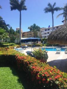 a resort with a swimming pool and palm trees and flowers at NEW Royal Pacific Condo 2 Pools Tennis Marina in Puerto Vallarta