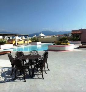 eine Terrasse mit einem Tisch und Stühlen neben einem Pool in der Unterkunft NEW Marina Vallarta Loft Pool BBQ Beach 5 mins in Puerto Vallarta