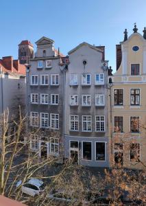 un gran edificio blanco con coches estacionados frente a él en Apartament Gdańsk Starówka, en Gdansk