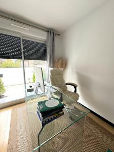 een woonkamer met een glazen tafel en een stoel bij La villa six_jml in Ris-Orangis