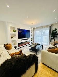 een woonkamer met een witte bank en een tv bij La villa six_jml in Ris-Orangis