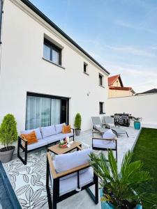 un patio con divani, tavoli e una griglia di La villa six_jml a Ris-Orangis