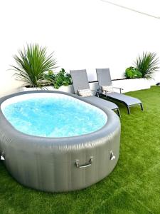 een hot tub in het gras met 2 stoelen bij La villa six_jml in Ris-Orangis