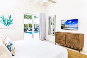 a white bedroom with a bed and a television at Caribbean Escape Luxe Waterfront Villa with Pool in Long Bay Hills