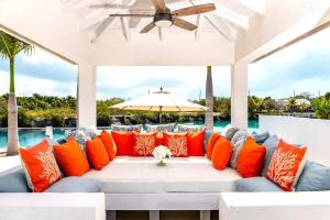 an outdoor couch with orange pillows on a patio at Caribbean Escape Luxe Waterfront Villa with Pool in Long Bay Hills