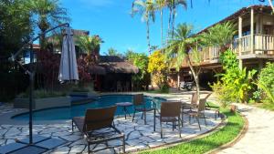 a patio with chairs and an umbrella next to a pool at Pousada North Shore Maresias - 2 quadras da praia - Casas de 2 quartos - 80 m2 -2 banheiros -piscina sauna - estacion-churrasq privativa -wifi animais de peq porte roupa de cama e banho in Maresias
