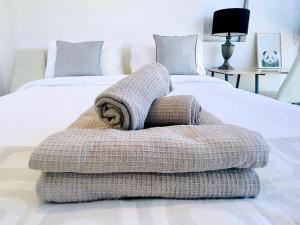 ein Bett mit zwei Handtüchern darüber in der Unterkunft Brand New Stylish 1BR Apartment, Specious Space, Free Parking, Self Check-in in Canberra
