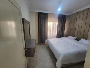 a bedroom with a white bed and a television at Gardens Company in Amman