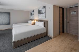 a bedroom with a bed with white sheets at Hotel Elements by Marquis in Mexico City
