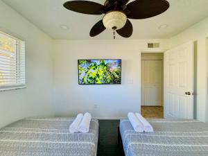 two beds in a room with a ceiling fan at Seaside Elegance 3 Mi to FM Beach Paradise Sleep 6 in Fort Myers Beach