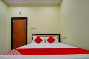 a bedroom with a bed with red pillows and a door at Flagship Hotel Pvs Grand in Vijayawāda