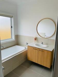 a bathroom with a tub and a sink and a mirror at Brand New House in Lakes Entrance in Lakes Entrance
